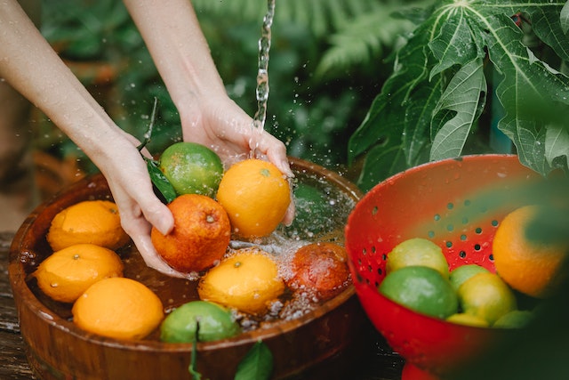 洗新鮮水果在熱帶果園裡的女人-蔬果清潔劑